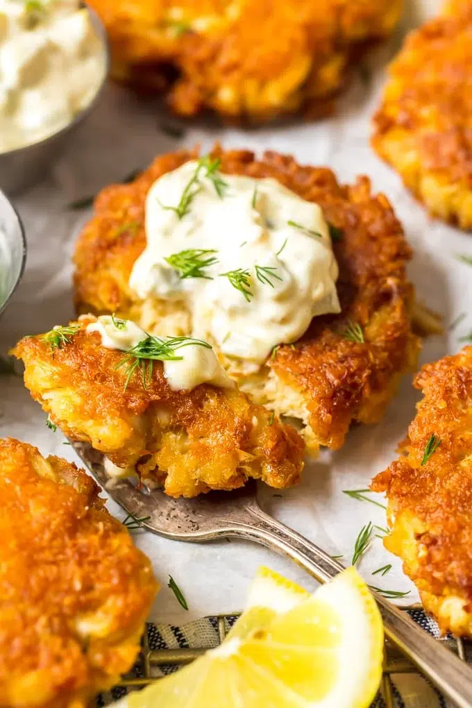 Homemade crab cake recipe with golden crust, served with lemon wedges and dipping sauce